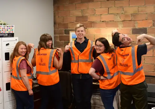 Abovo team wearing Great Plains Food Bank volunteer vests they designed, standing together and smiling.