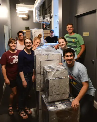 Team Abovo standing in front of a pallet of packed boxes ready for the North Dakota FFA state convention, showcasing their dedication and support.